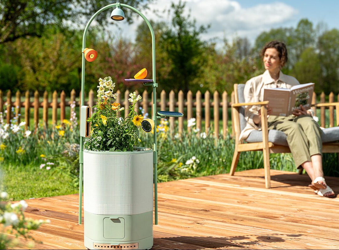 A vibrant backyard or balcony featuring a Wonder Blocks modular habitat system with various components like planters and a water feature, with a "Petal" AI-enabled camera subtly integrated, and a bee or butterfly actively interacting with the habitat.