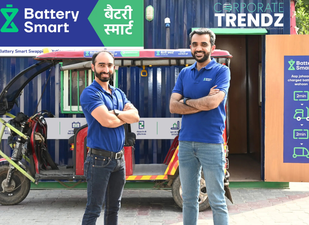 Battery Smart team, including founders Pulkit Khurana and Siddharth Sikka, celebrating a funding milestone in front of an EV battery swapping station, showcasing their innovative solution for electric vehicles.