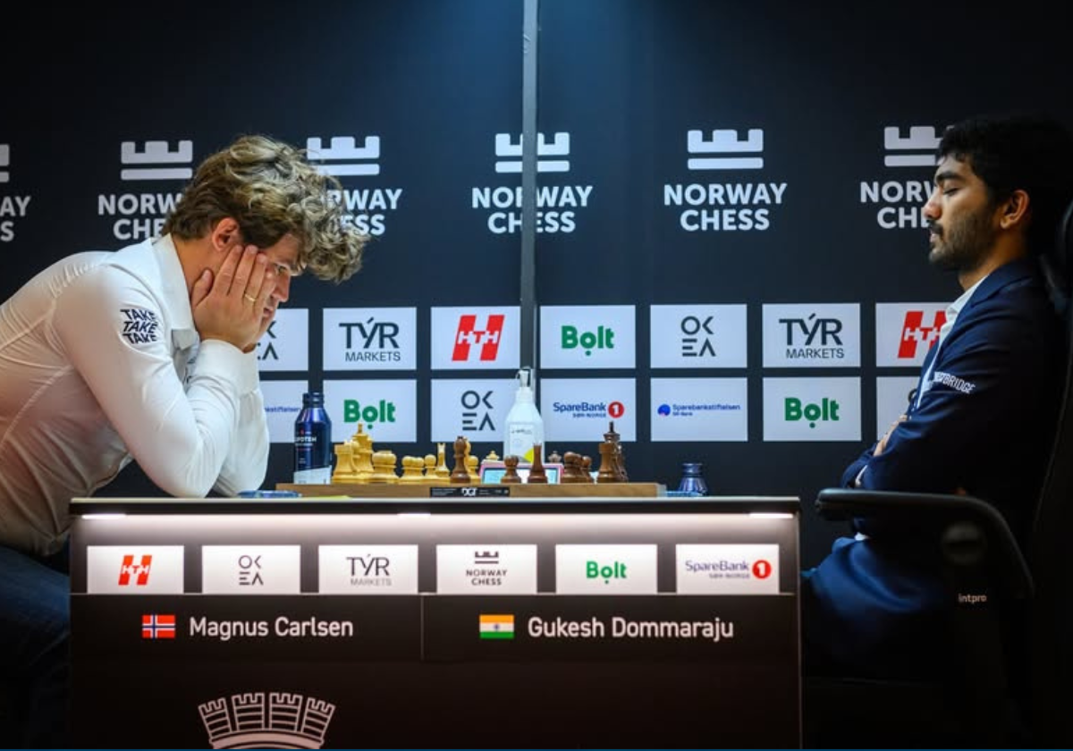 Gukesh Dommaraju looking calm and focused at a chess board, with Magnus Carlsen in the background showing visible frustration.