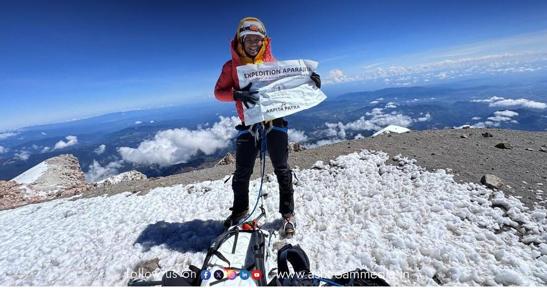 IISc Professor Arpita Patra planting a flag on the snowy summit of a volcanic peak, celebrating her high-altitude climb.